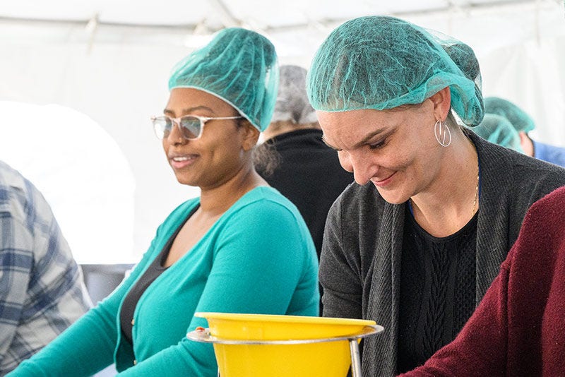 Amica volunteers smiling while putting together soup meals.