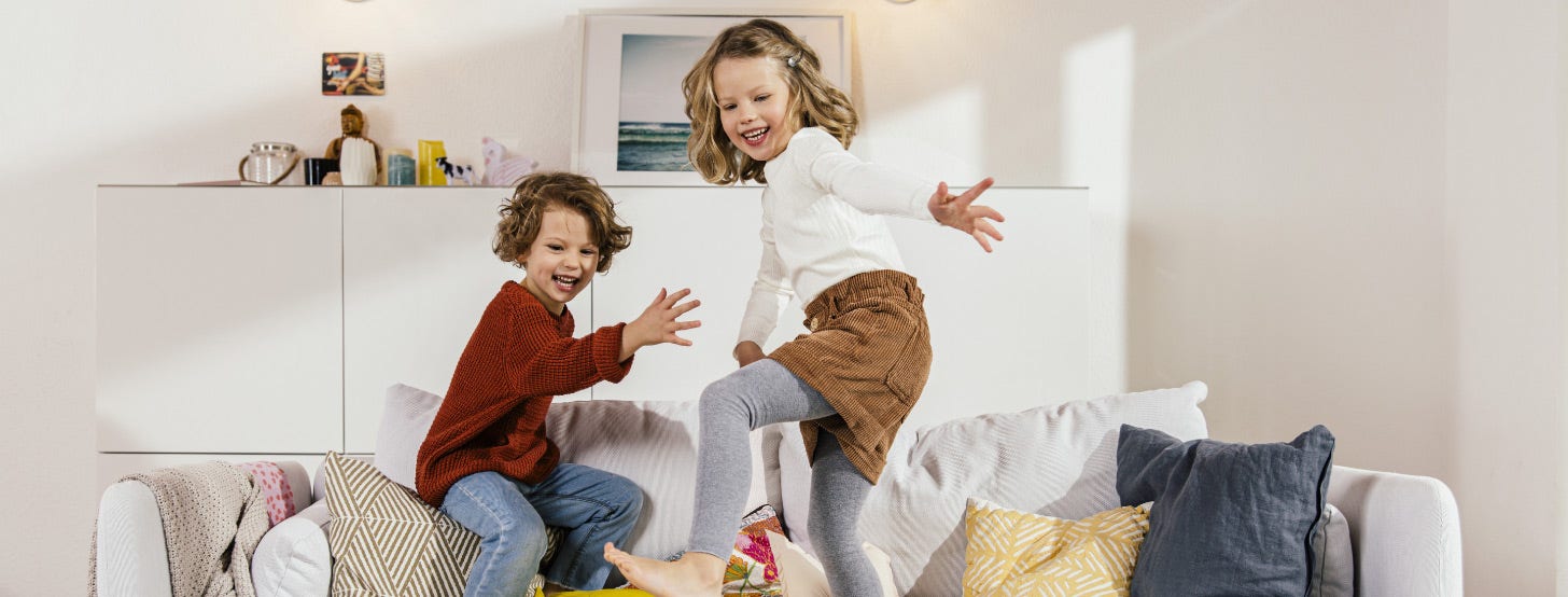 Two children playing on a couch.