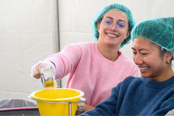 Amica volunteers smiling while putting together soup meals.