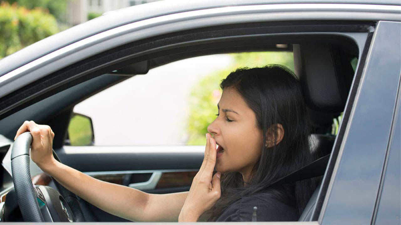 Woman yawning while driving car