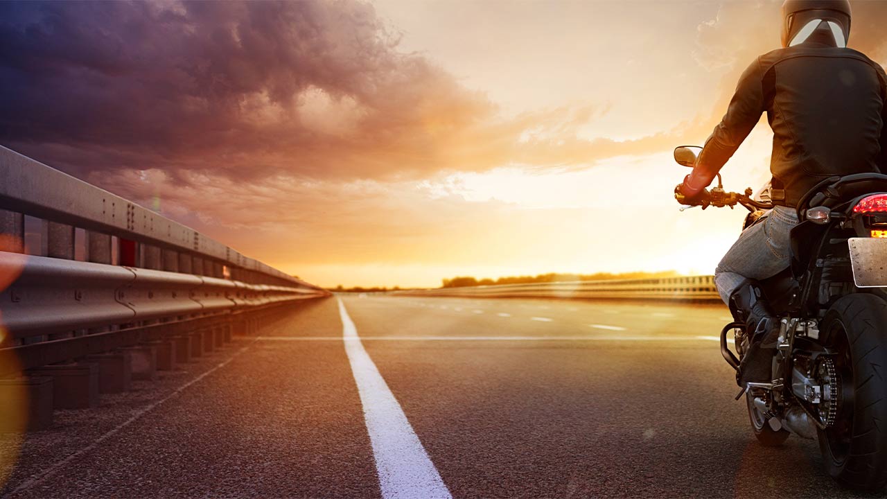 A motorcyclist riding down the highway on his motorcycle at sunset
