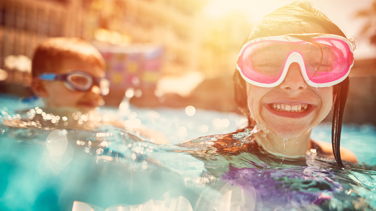 brother and sister swimming in a pool with goggles