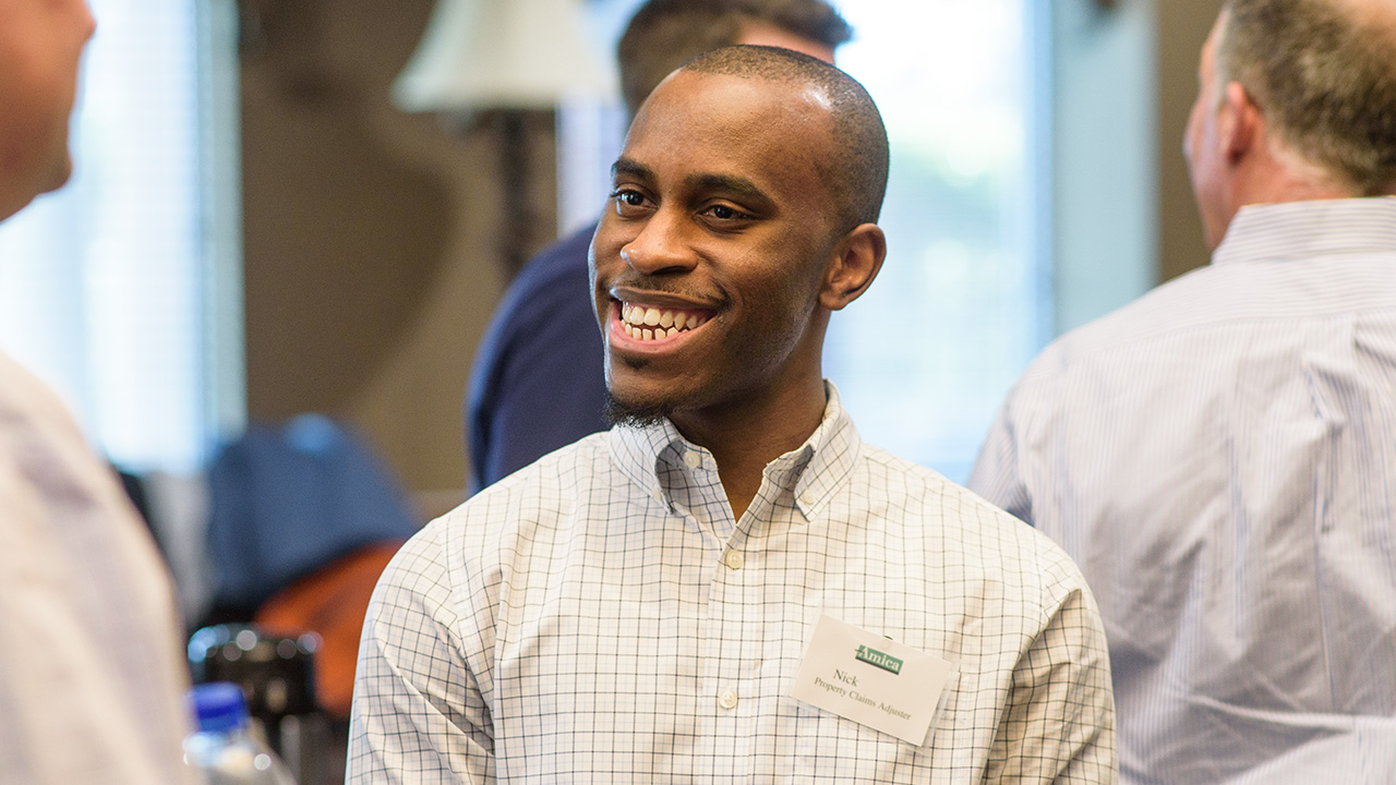 Smiling male employee wearing Amica nametag at company function