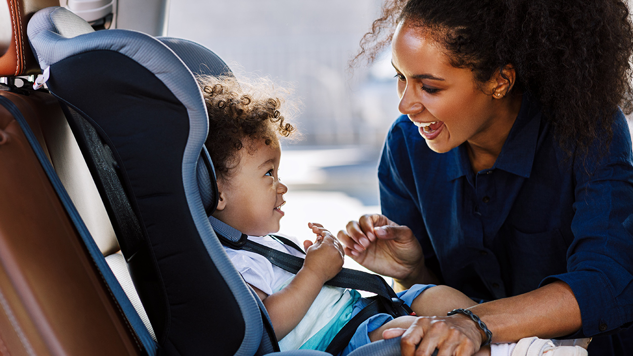 Woman buckles child into car seat