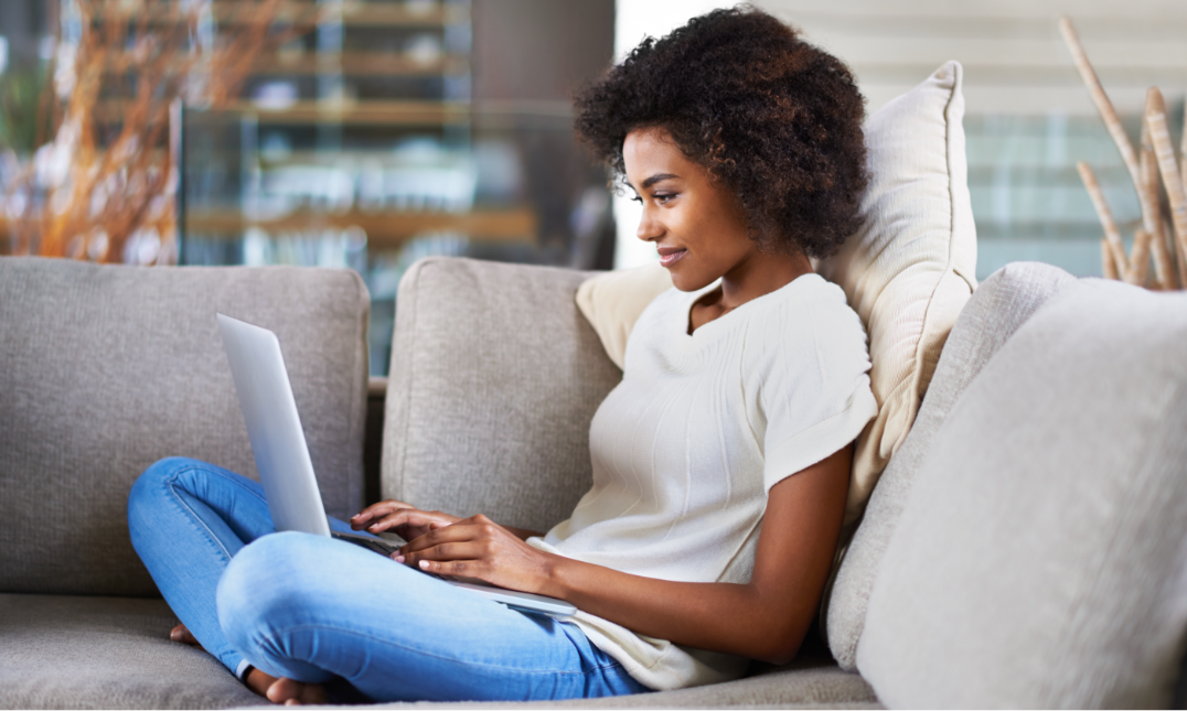 Young woman sitting on her couch looking at her laptop: Identity fraud expense coverage: Consider adding ID theft protection