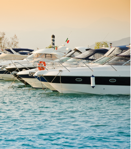 Multiple yachts anchored in line against late afternoon sky on rippling water