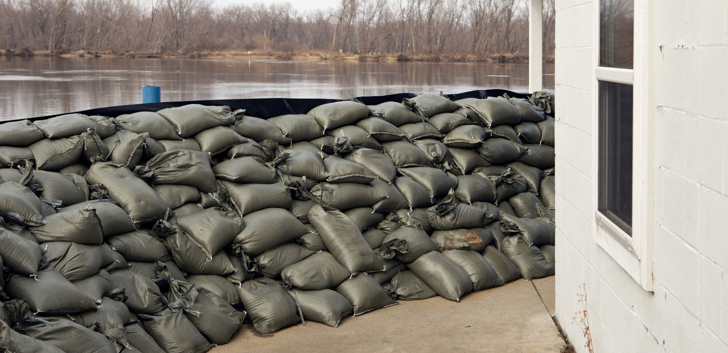 A house with sandbags piled high against floodwater.
