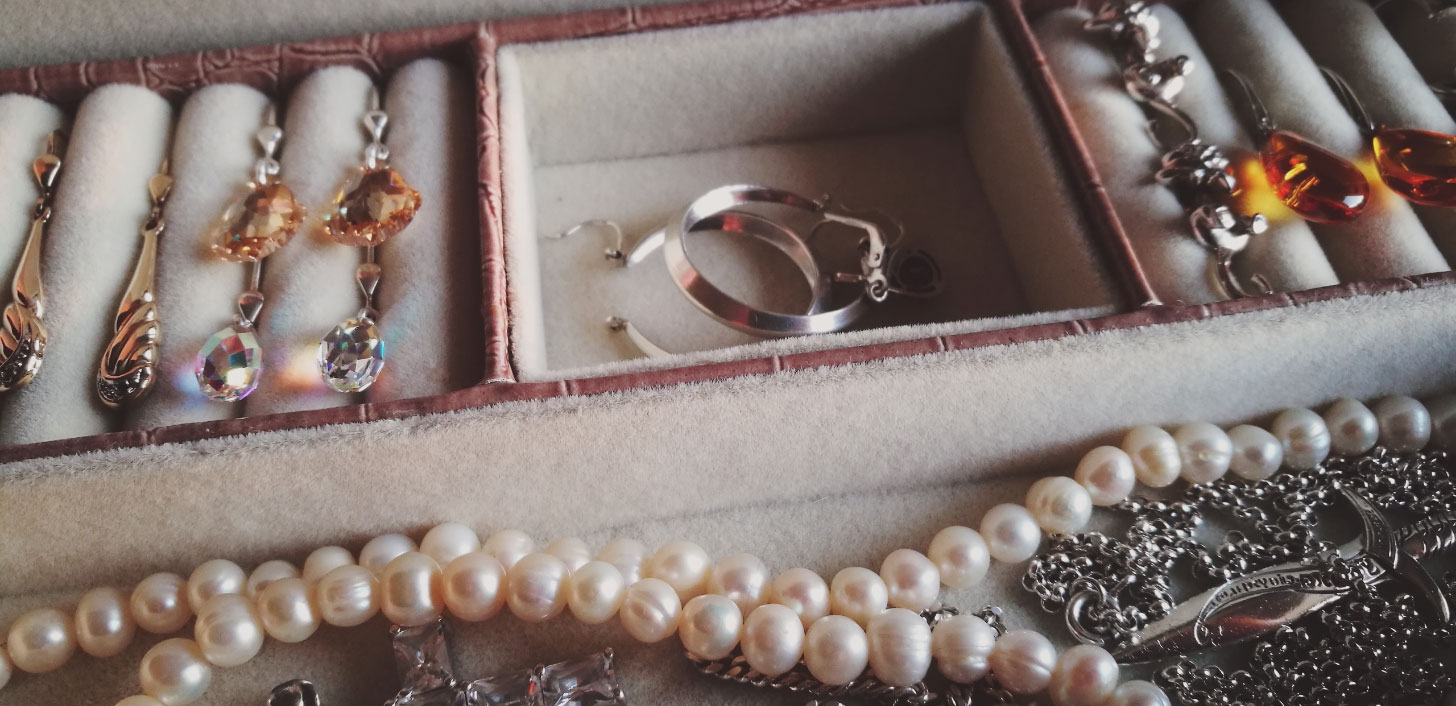 A jewelry box with earrings, rings and a pearl necklace.