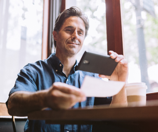 Dividend payment options:Another great thing about dividend policies is you get to choose how you receive and use your payment: A man is holding up a phone in his left hand and what appears to be a check directly below the phone with right hand